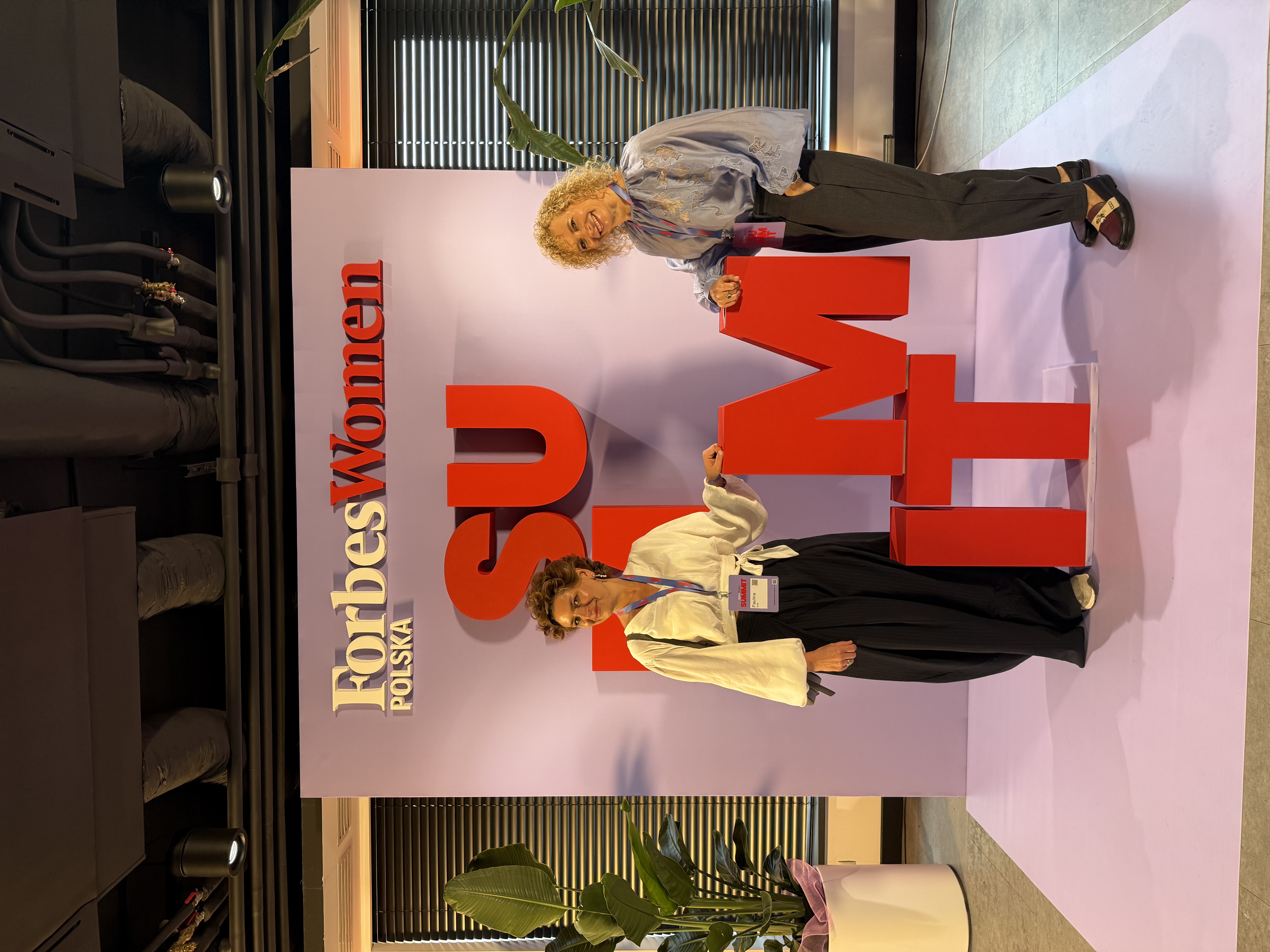 Paulina Kruk with another participant in front of the Forbes Women backdrop